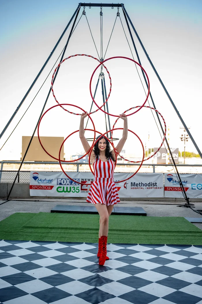 circus performer holding 6 hula hoops in the shape of a 6 ring mandala