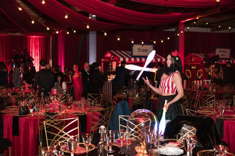 A juggler is walking around a venue juggling 3 juggling clubs